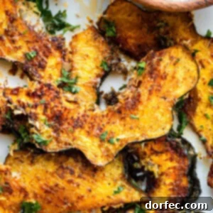 A photo of several slices of roasted acorn squash with fresh parsley sprinkled on top
