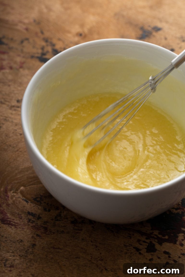 A bowl of white chocolate butter sauce being whisked to creamy perfection, highlighting its smooth and luscious texture.