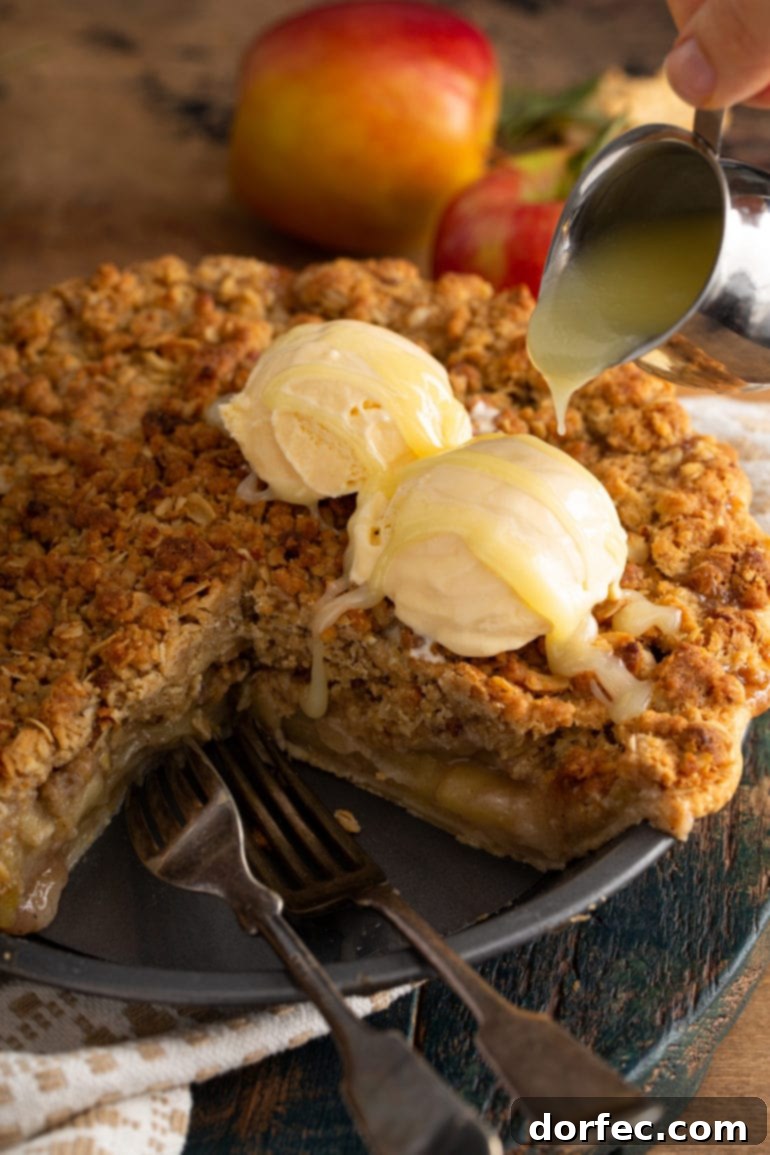 A magnificent Dutch apple pie with a slice removed, revealing two generous scoops of vanilla ice cream melting slightly on its warm surface, all elegantly drizzled with the rich white chocolate butter sauce.