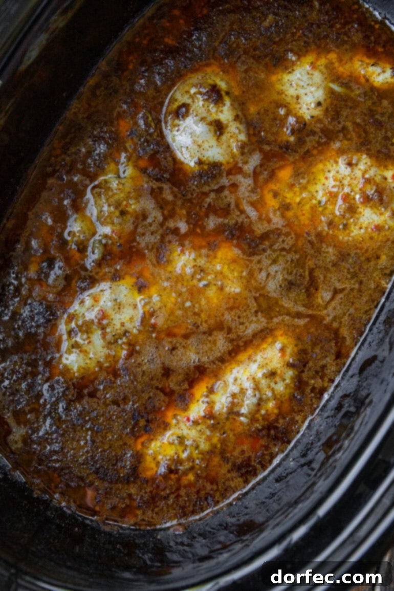 Cafe Rio Shredded Chicken: An Authentic Taste of the Southwest 5 Chicken breasts in seasoned cooking liquid in a slow cooker