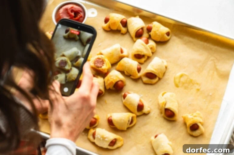 Person taking a picture of pigs in a blanket