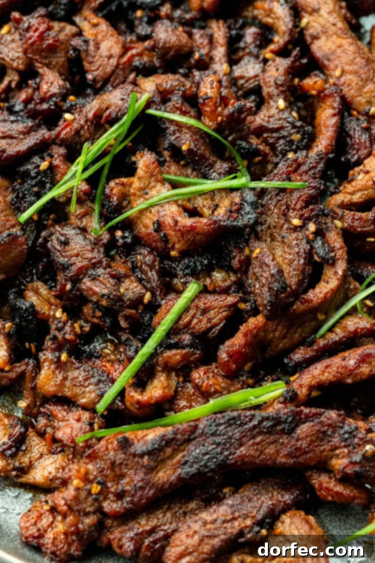 Close-up of saucy Korean BBQ Beef Bulgogi with sesame seeds and green onions
