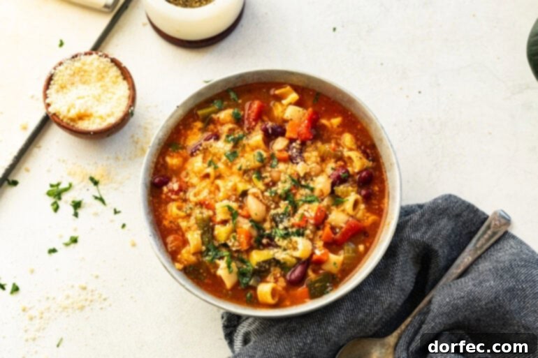 Grandma's Secret-Recipe Minestrone 7 A steaming bowl of Minestrone soup served in a white ceramic bowl, filled with colorful vegetables, beans, and pasta, and topped with fresh herbs.