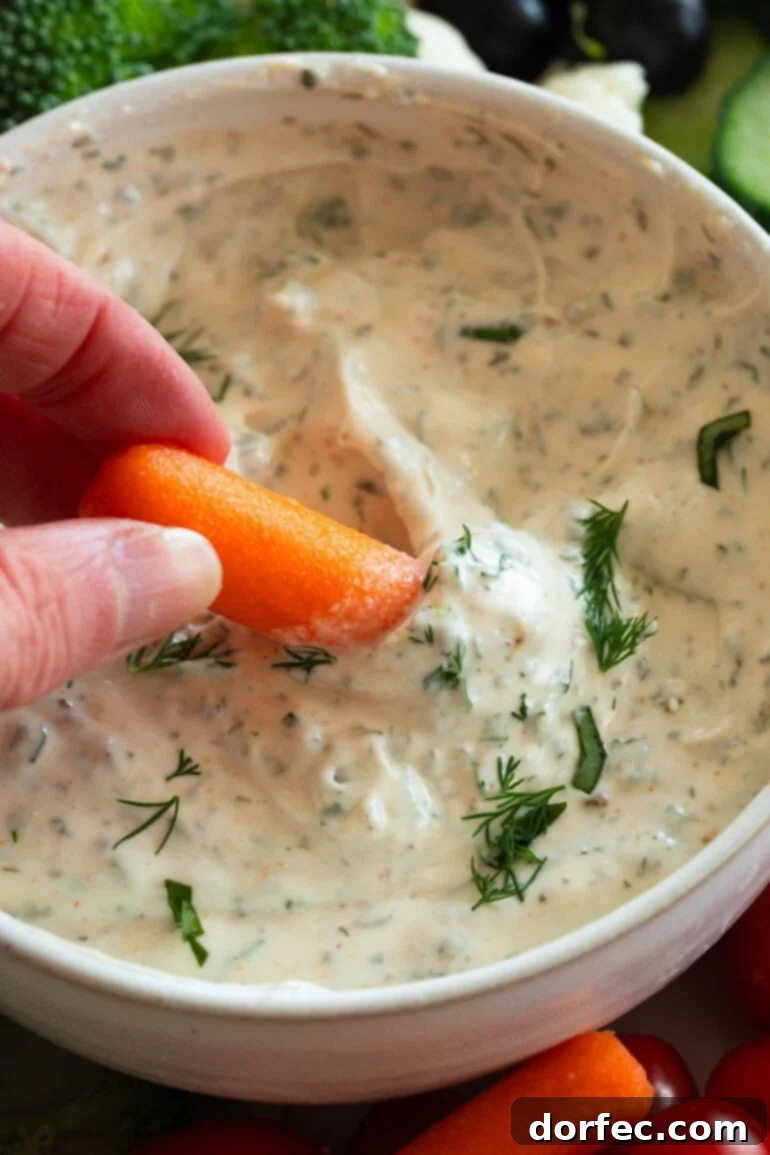 Creamy Herb and Garlic Vegetable Dip 3 Dipping a carrot in creamy garlic herb veggie dip
