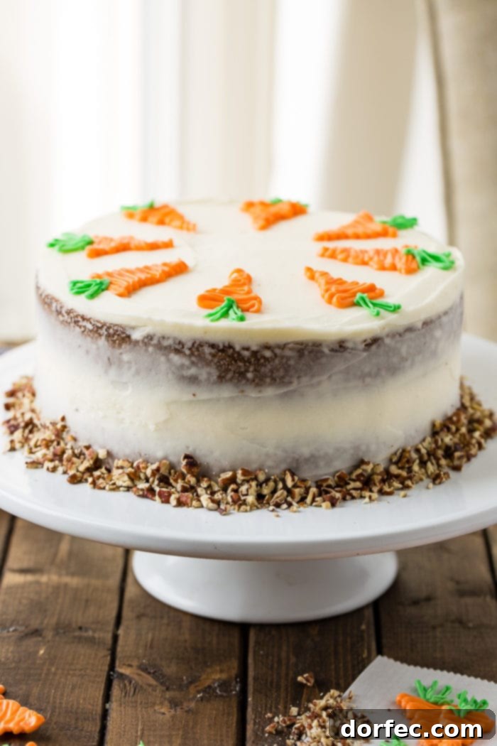 Ultimate Carrot Cake: Unbelievably Moist and Frosted to Perfection 7 Two-layer carrot cake on a white cake stand with cream cheese frosting and white chocolate carrots