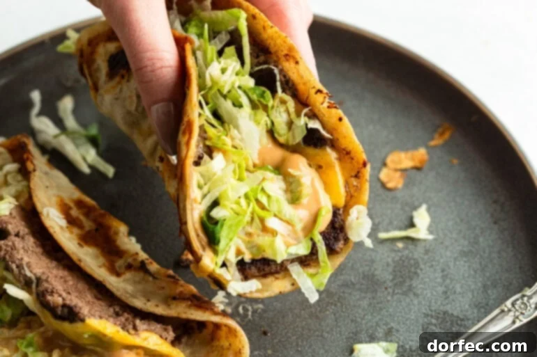 Smash Burger Taco held over a plate of ingredients