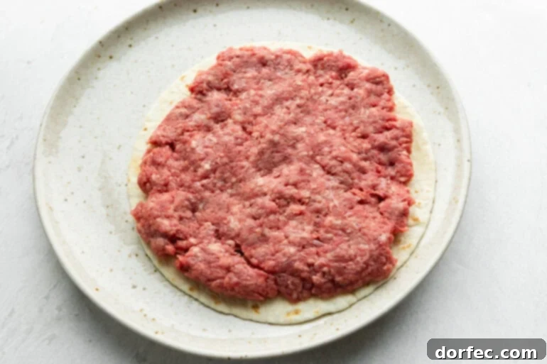 Ground beef smashed onto a flour tortilla