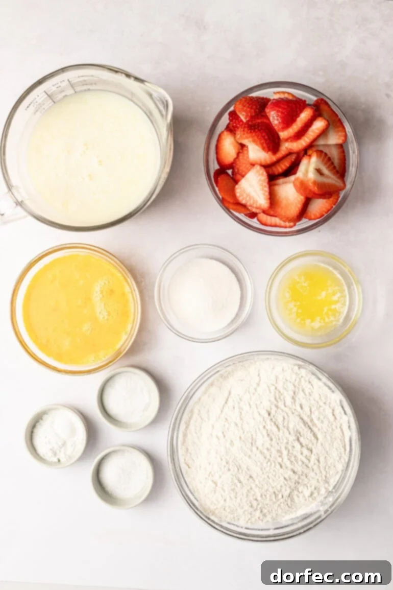 One Pan Strawberry Pancakes 6 All the individual ingredients for sheet pan pancakes laid out in small glass bowls, including flour, buttermilk, sugar, eggs, baking powder, baking soda, melted butter, and sliced fresh strawberries.
