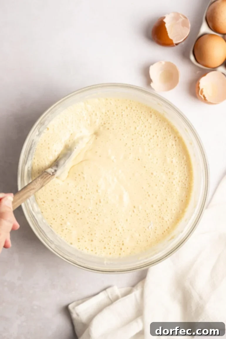 One Pan Strawberry Pancakes 10 Step-by-step image of folding melted butter into pancake batter.