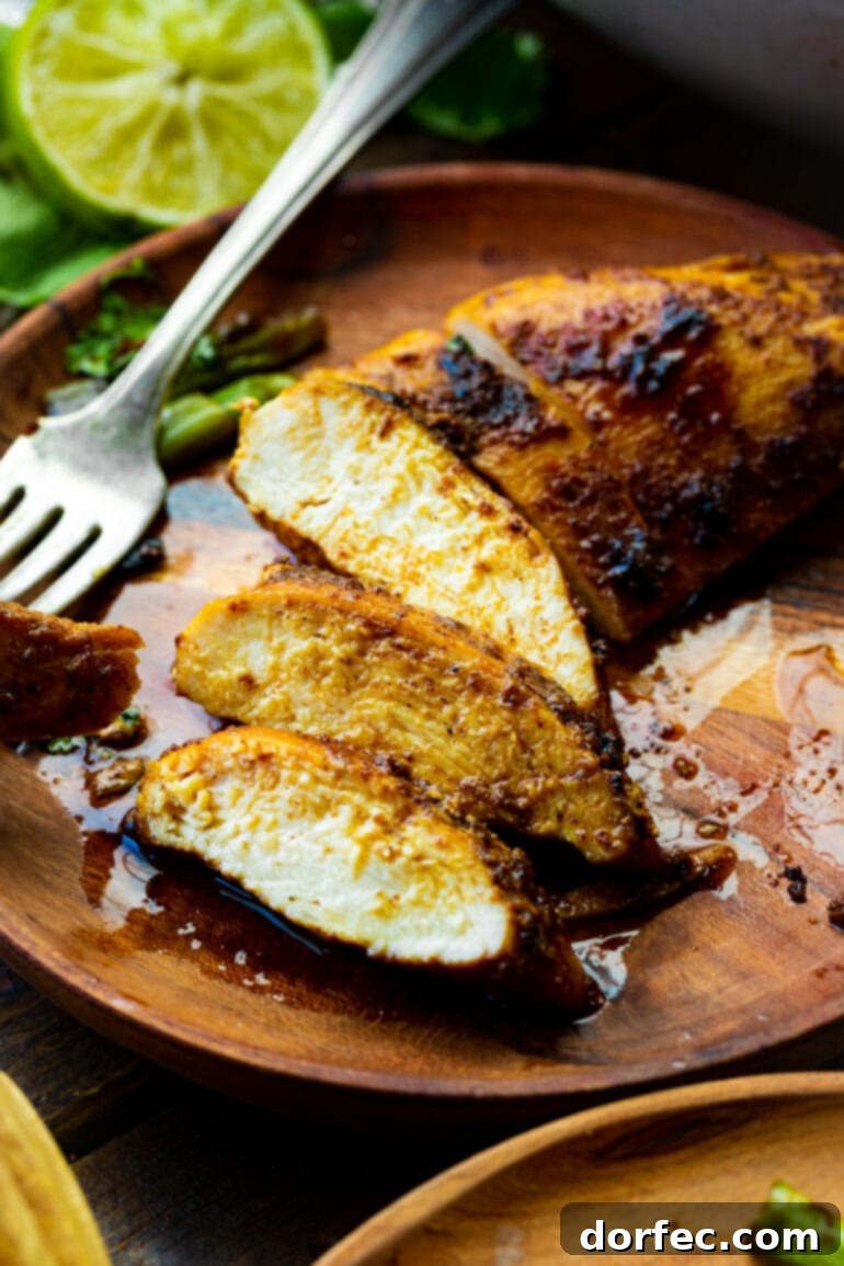 A close-up photo of a perfectly pan-seared chicken breast, with a few slices removed to reveal the juicy, tender interior of the meat.