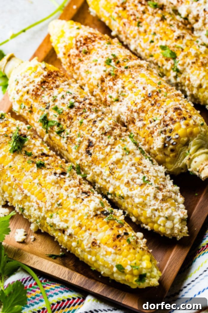 A captivating photo of several cobs of Elote Mexican Street Corn, generously lathered in creamy cotija cheese and savory seasonings.