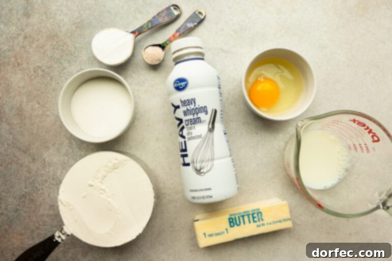 Ingredients for sweet cream biscuits laid out, including flour, butter, sugar, heavy cream, and an egg.