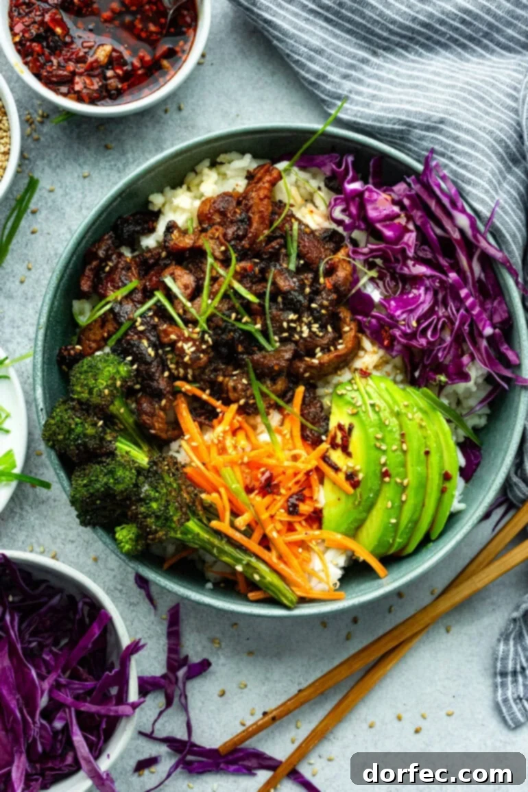 A close-up of a Korean beef rice bowl, showcasing tender beef strips and fresh vegetables.