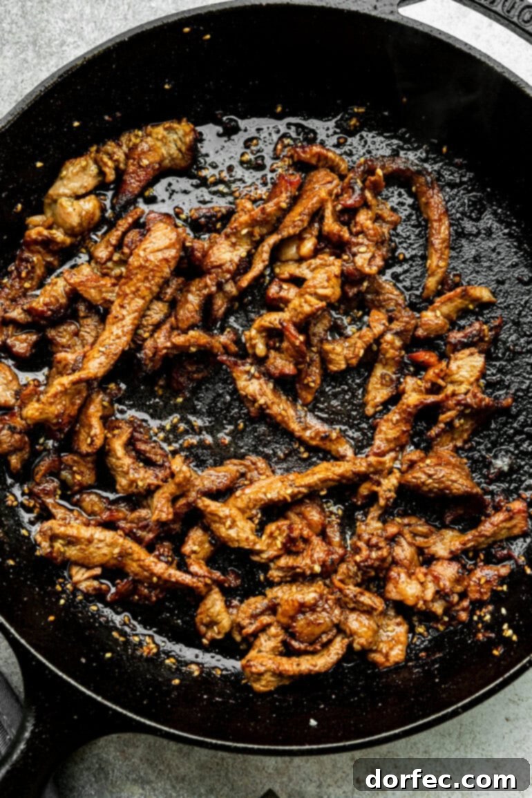 Sizzling thin slices of marinated beef cooking in a cast iron skillet for the bulgogi bowls.