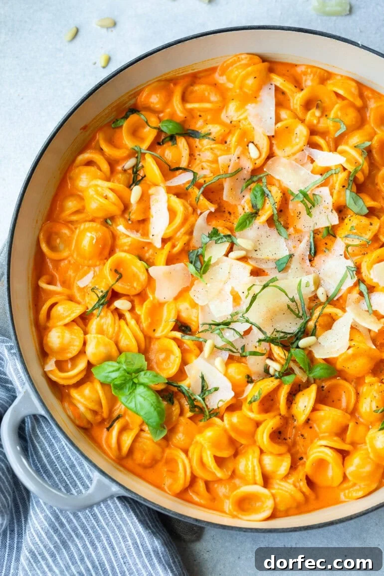 a large dutch oven full of cooked orecchiette pasta mixed with creamy roasted red pepper pasta 