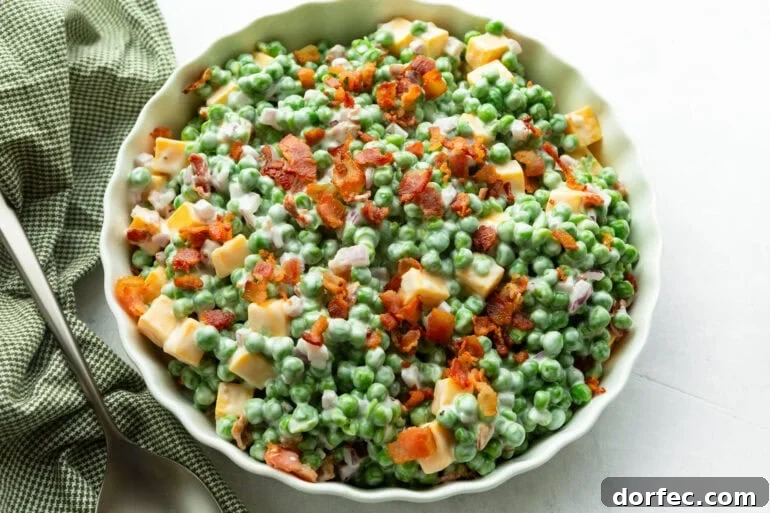 a large bowl of creamy pea salad topped with crispy bacon bits