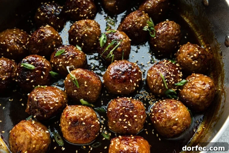 sweet and savory korean meatballs sitting in a sticky sauce with green onions and sesame seeds sprinkled over the top
