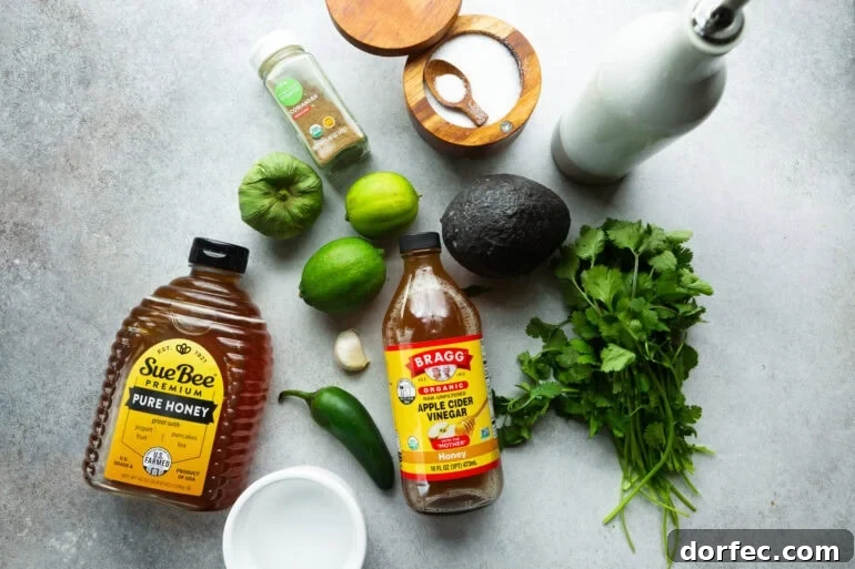 all the ingredients for cilantro lime dressing including cilantro, avocado, limes, apple cider vinegar, honey, jalapeno, tomatillo, and seasonings