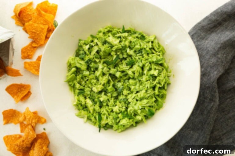 A close-up of the finished chopped green goddess salad in a white serving bowl, ready to be eaten.