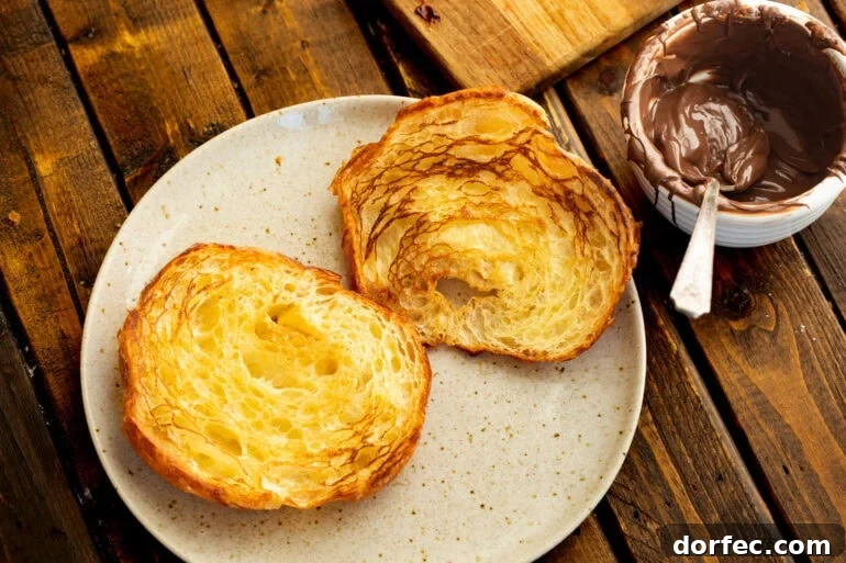 Grilled Croissants with Strawberry and Nutella Filling 3 a grilled sliced croissant sits on a plate next to an open jar of nutella for strawberry nutella croissants