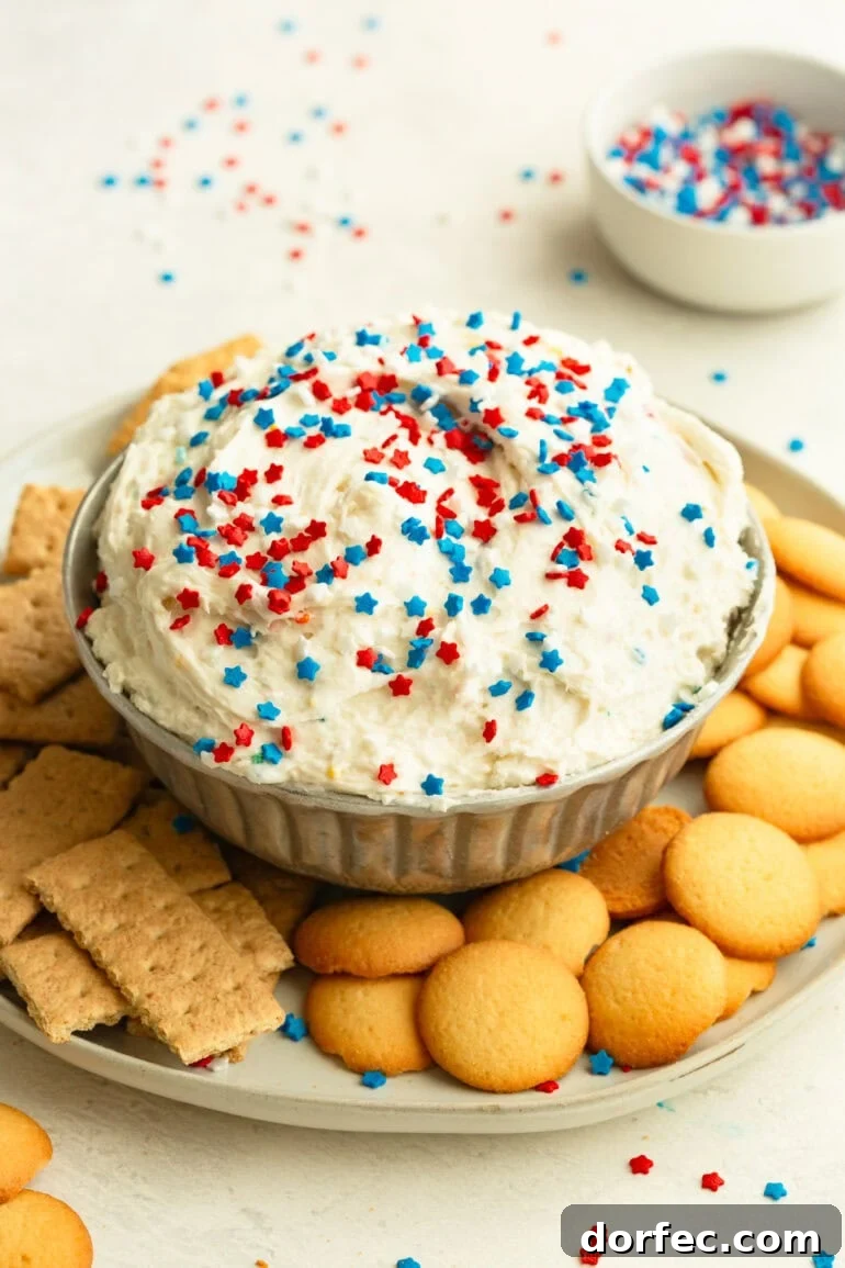Patriotic dessert dip decorated with red white and blue sprinkles in a party spread.