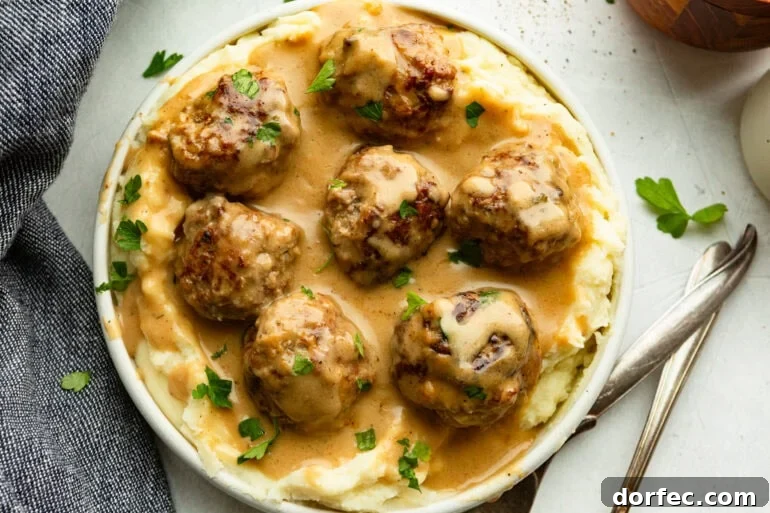 Authentic Swedish Meatballs with Creamy Gravy 2 a bowl of creamy Swedish meatballs on a bed of mashed potatoes and sprinkled with fresh parsley