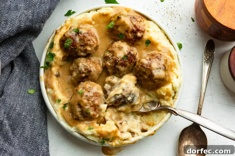 Authentic Swedish Meatballs with Creamy Gravy 8 a spoon scooping up a Swedish meatball on top of mashed potatoes