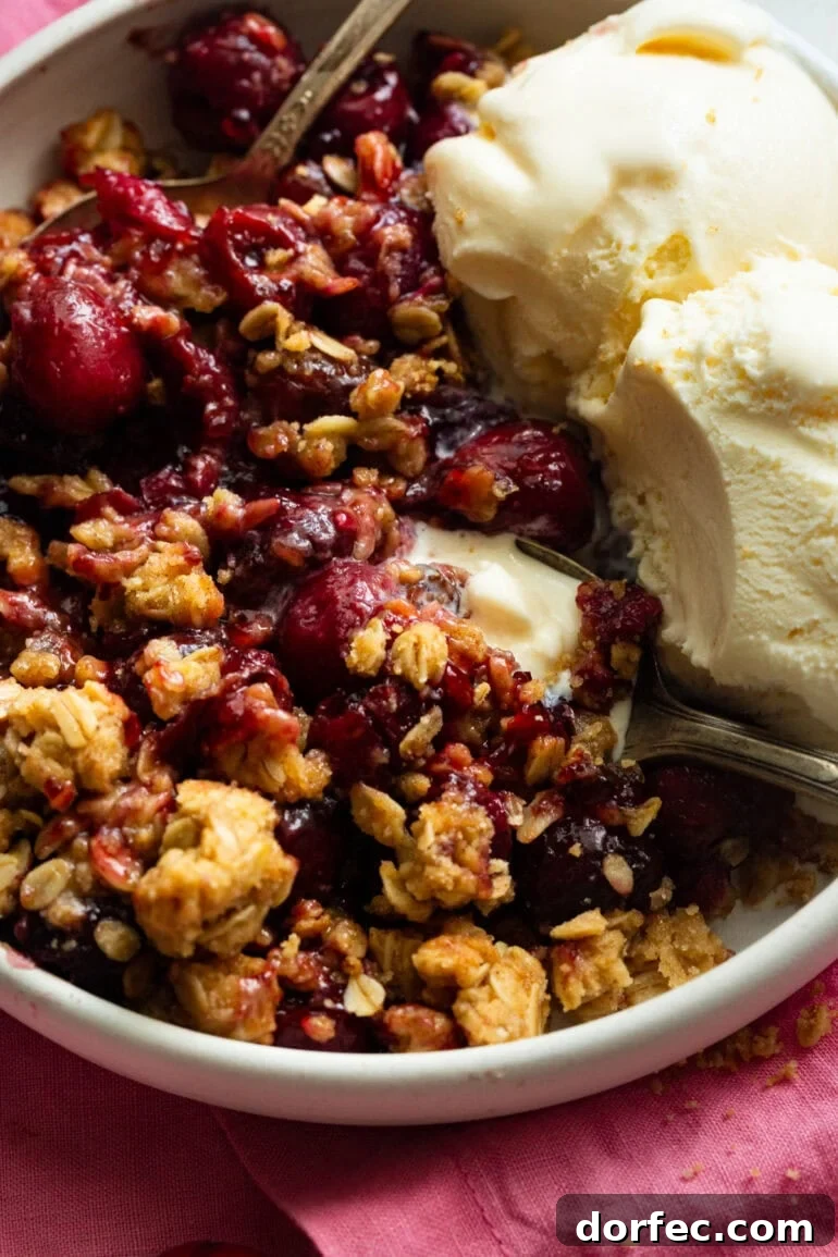 Homemade Old Fashioned Cherry Crisp Recipe 3 someone scooping up a bit of cherry crisp with vanilla ice cream on the side